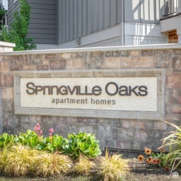 Discover convenient living at Springville Oaks! a sign for Springville Oaks in a flower bed